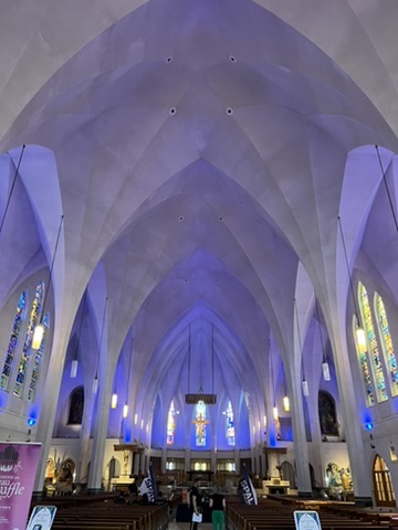 The vaulted church interior lit in blue with stained glass windows.