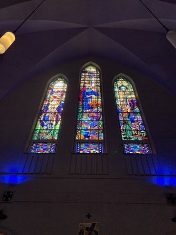 Three stained glass church windows illuminated by blue light.
