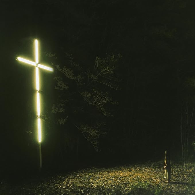 A luminous cross standing in a dark forest clearing.