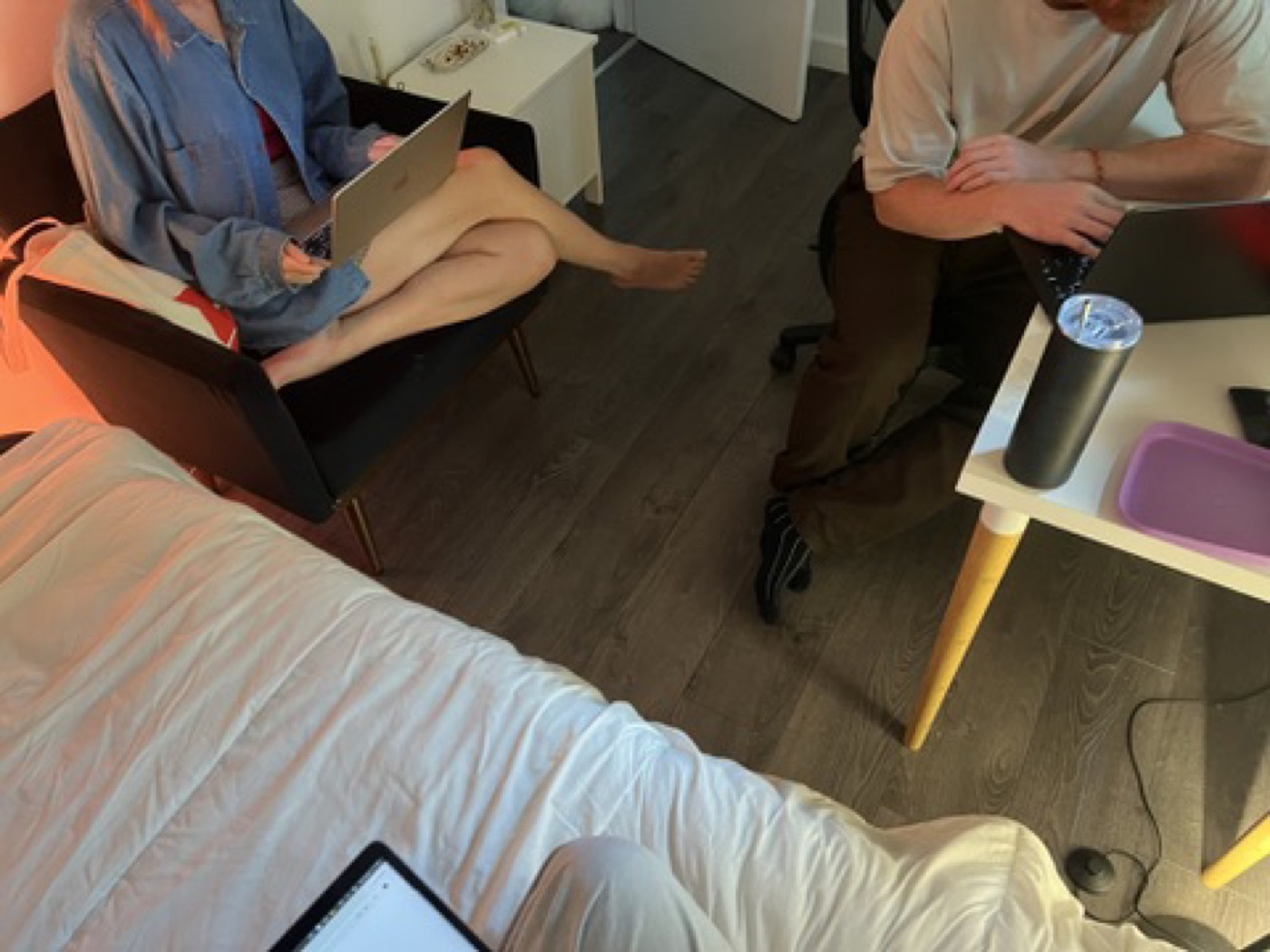 Two people working with laptops in a small room session.
